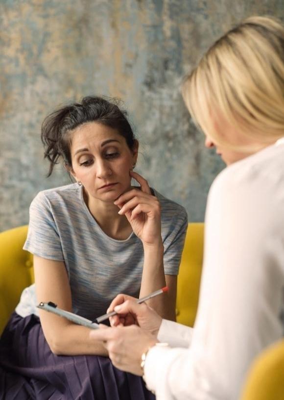 Psychiatrist holding a clipboard speaking with patient