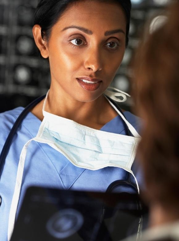 Image of doctor with mask around her neck speaking with another Vituity physician